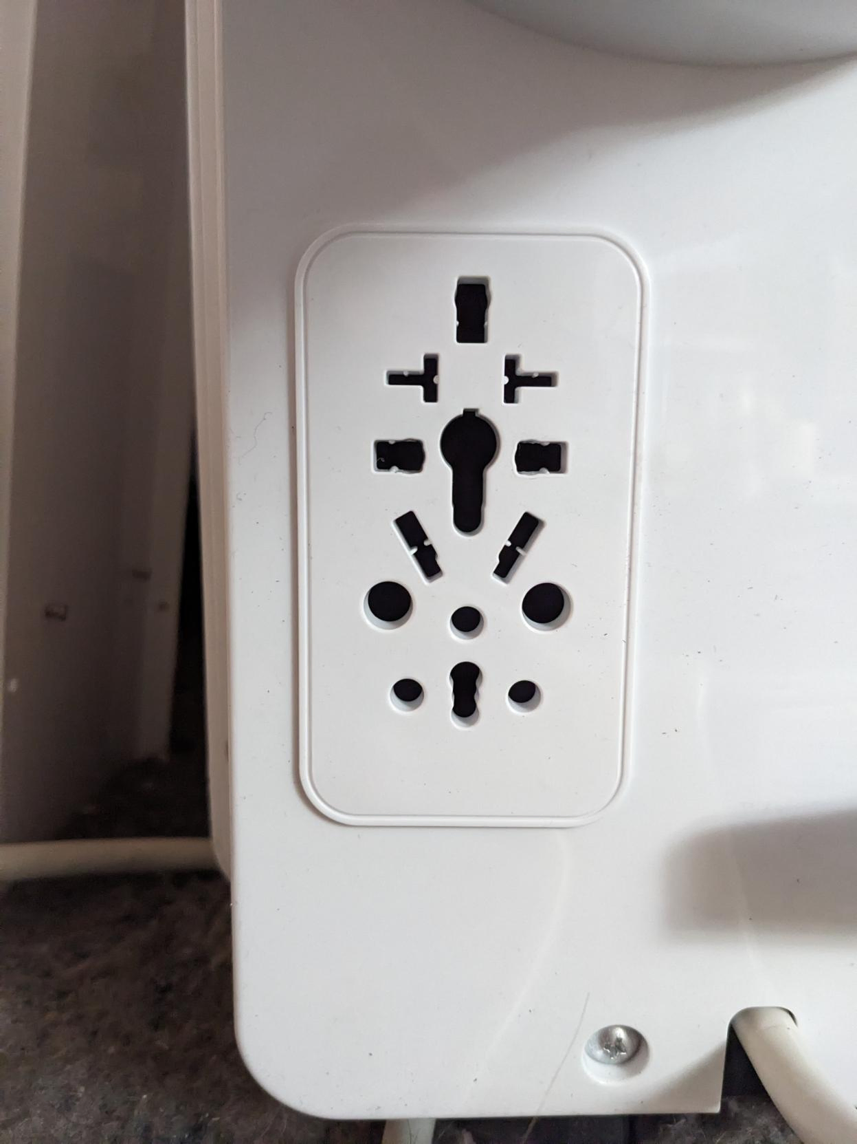 A picture of a power outlet with holes for many different countries' layouts.
